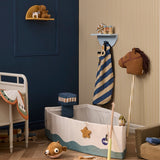 Plush brown hobby horse on a wooden stick in a child's bedroom with toys and a boat play set.