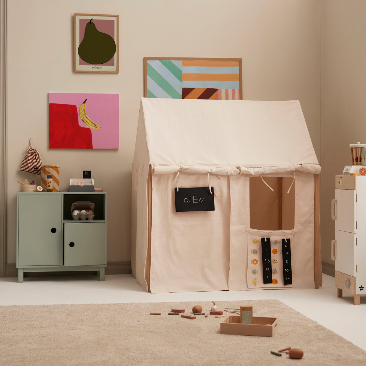 Off-white play house tent set up as a pretend store with an OPEN sign in a playroom.