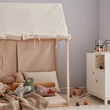 Off-white play house tent filled with plush toys and cushions in a cozy playroom.