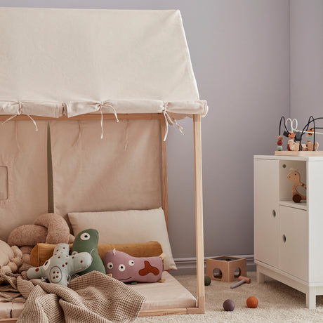 Off-white play house tent filled with plush toys and cushions in a cozy playroom.