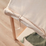 Close-up of off-white fabric tied to the wooden frame of a play house tent.
