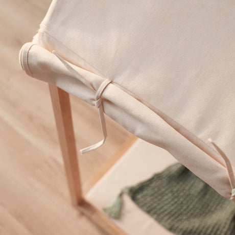 Close-up of off-white fabric tied to the wooden frame of a play house tent.