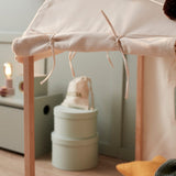 Close-up of off-white play house tent tied to wooden frame with colorful pom-pom garland on top.