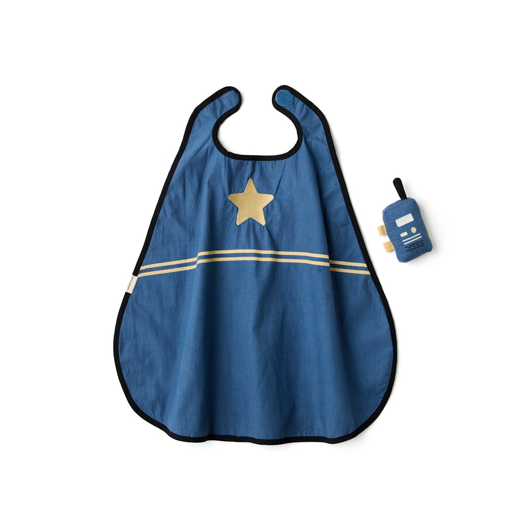 A stylish blue and beige striped cape with a gold star, next to a plush toy resembling a vintage radio, laid in a white background.