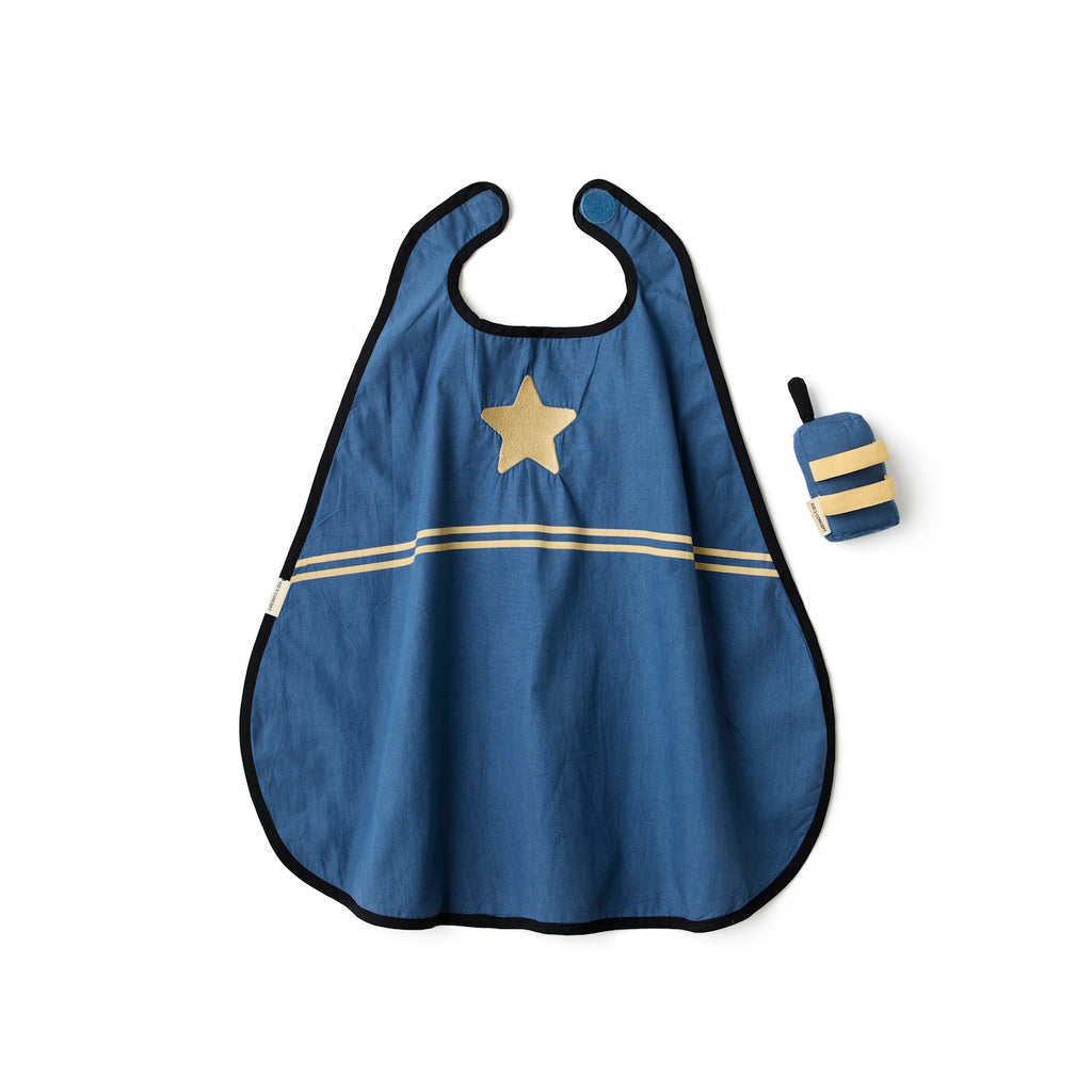 A stylish blue and beige striped cape with a gold star, next to a plush toy resembling a vintage radio, laid in a white background.