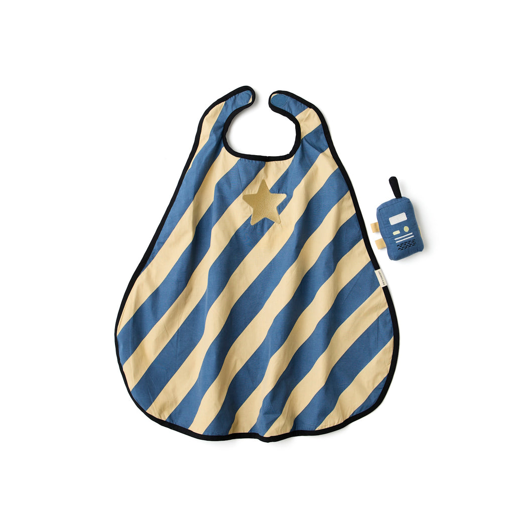 A stylish blue and beige striped cape with a gold star, next to a plush toy resembling a vintage radio, laid in a white background.