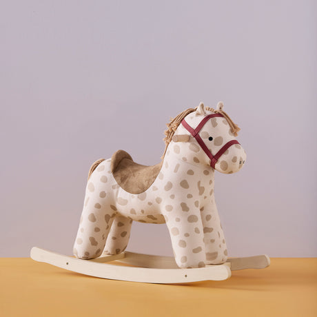 Kids Concept Dotty beige plush rocking horse toy with wooden runners on a yellow surface.