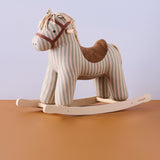 Striped plush rocking horse toy with a brown suede saddle on wooden runners.