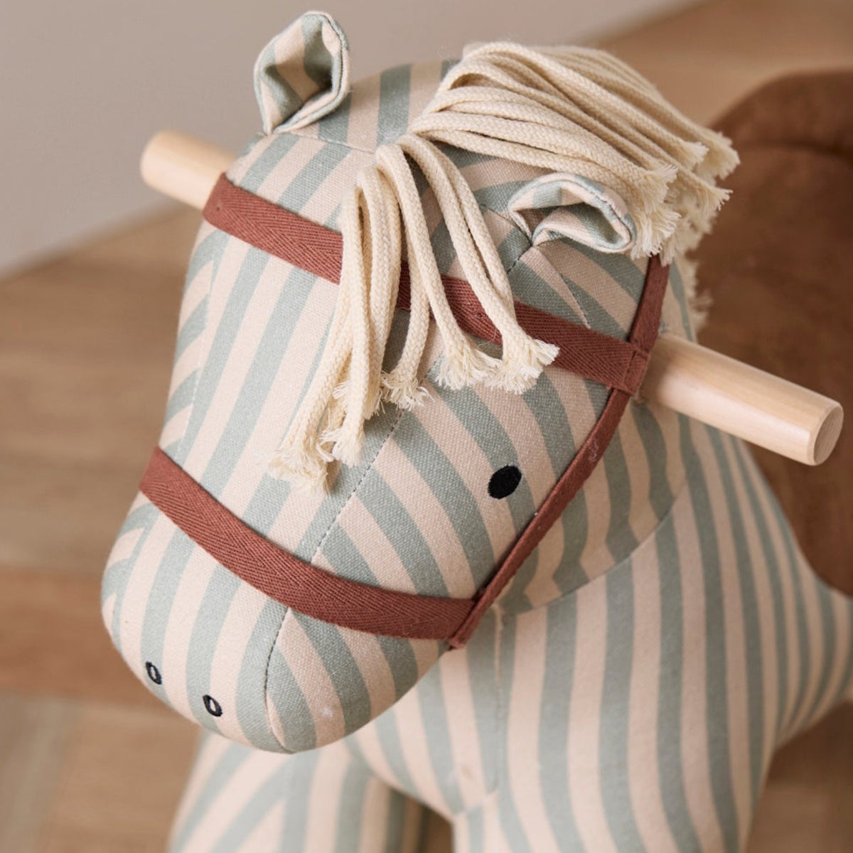 Close-up of the head and yarn mane of a striped fabric rocking horse toy.
