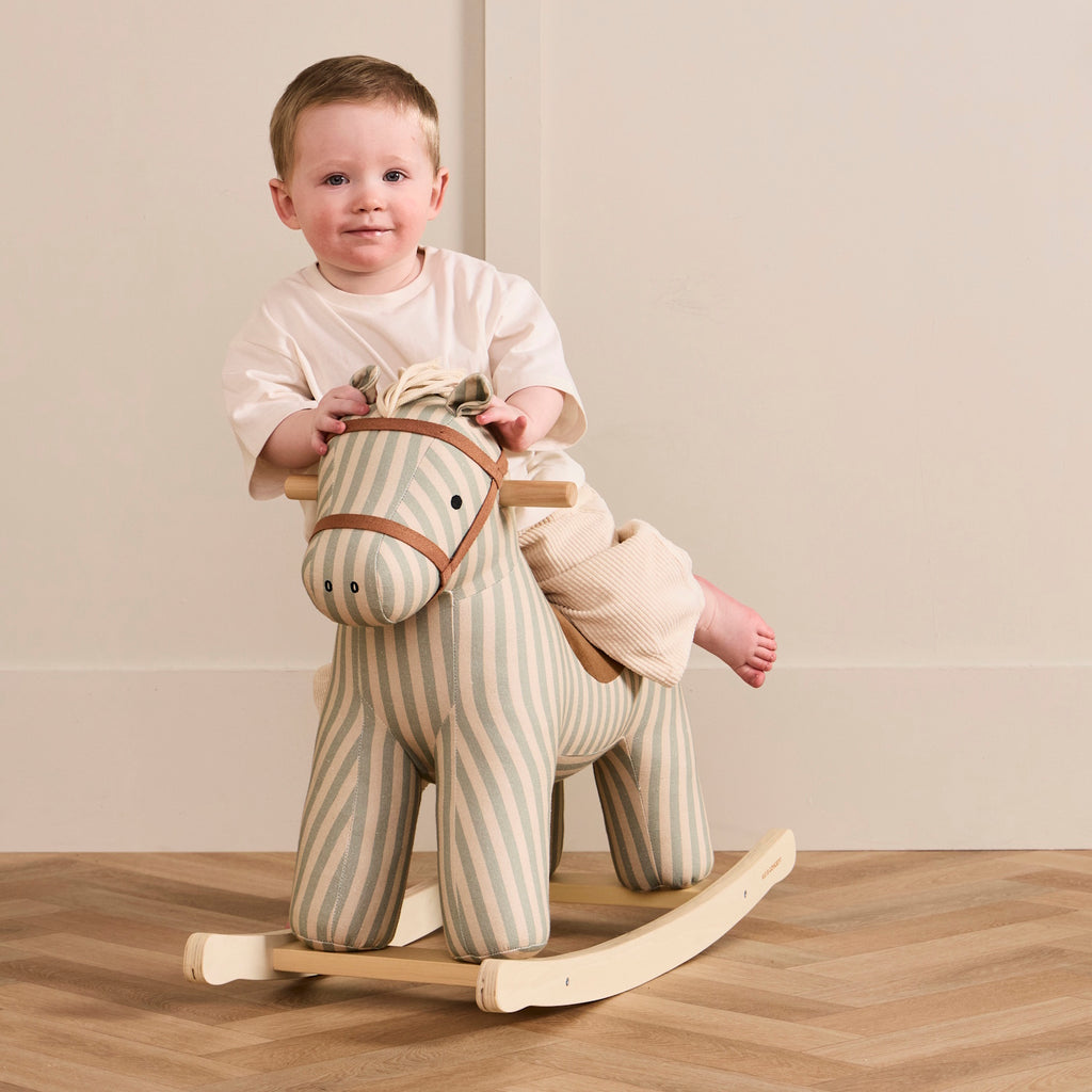 Soft, striped rocking horse with a beige and blue pattern, wooden rockers, and a plush brown saddle. It evokes a playful, nostalgic feel.