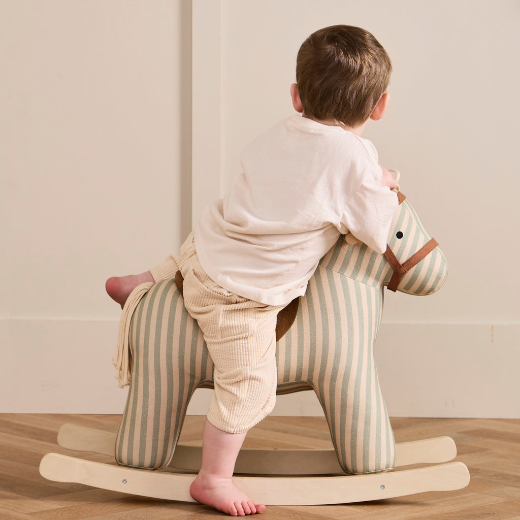 Soft, striped rocking horse with a beige and blue pattern, wooden rockers, and a plush brown saddle. It evokes a playful, nostalgic feel.
