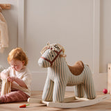 Red-haired toddler playing on the floor next to a striped plush rocking horse toy.