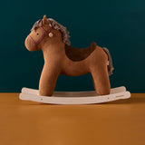 Brown corduroy plush rocking horse on wooden rockers against a dark teal wall and tan floor.