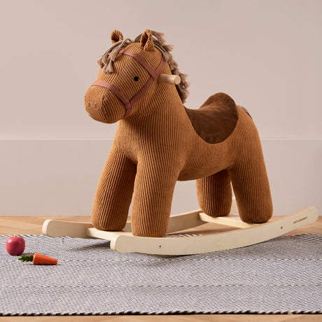 Plush brown corduroy rocking horse with wooden runners standing on a blue pattern rug.