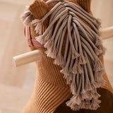 Close-up of a brown corduroy rocking horse showing its braided yarn mane and wooden handles.