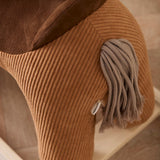 Close-up of a brown corduroy rocking horse toy showing its yarn tail and plush saddle details.