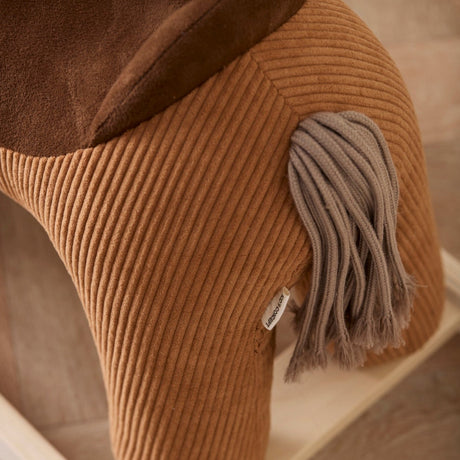 Close-up of a brown corduroy rocking horse toy showing its yarn tail and plush saddle details.