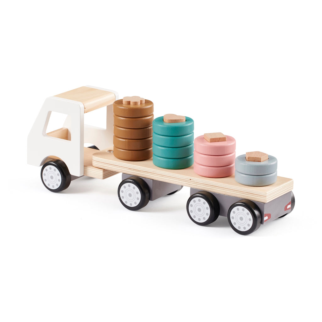 A wooden toy truck with a white cab and black wheels. The flatbed carries cylindrical wooden stacks in gray, pink, teal, and brown, creating a playful and organized look.