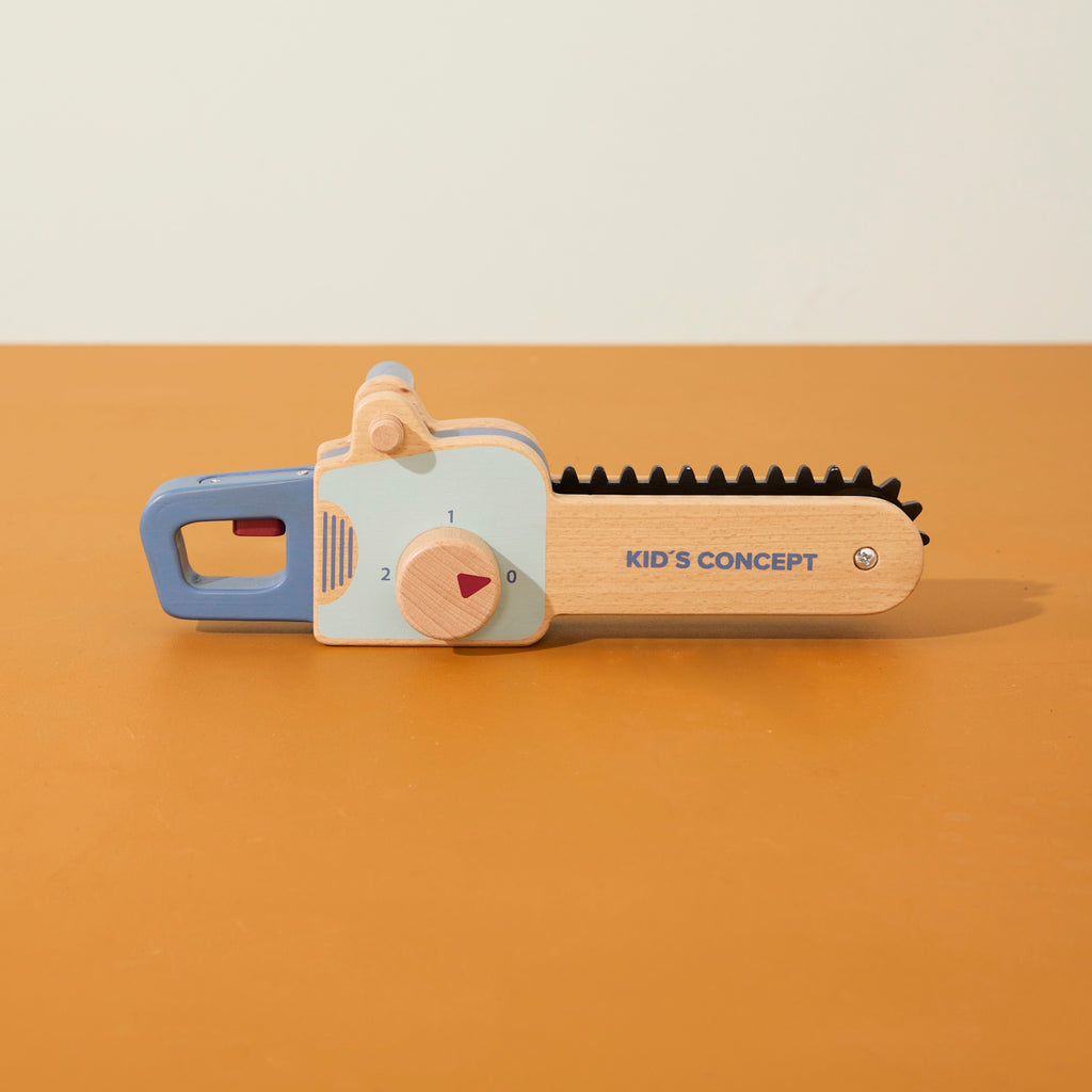 Wooden toy chainsaw with blue handle and details, featuring a rotating knob and black ridged edge. "Kid’s Concept" is printed on the side.