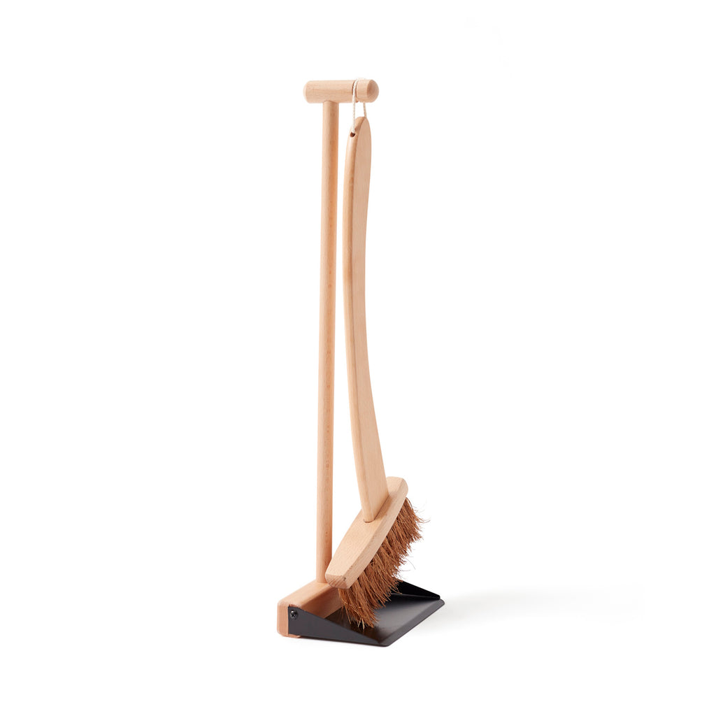 Wooden broom and dustpan set with a sleek, minimalist design. The broom features natural bristles and hangs from a matching stand, conveying simplicity.
