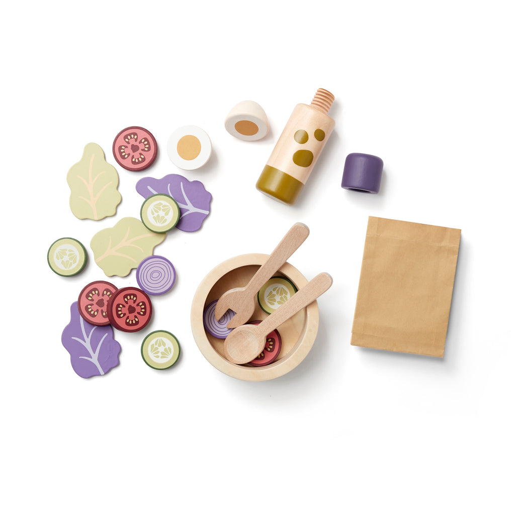 Wooden toy salad set with a bowl, utensils, slices of vegetables, and a bottle. Items are colorful, playful, and spread out, conveying a fun, culinary theme.