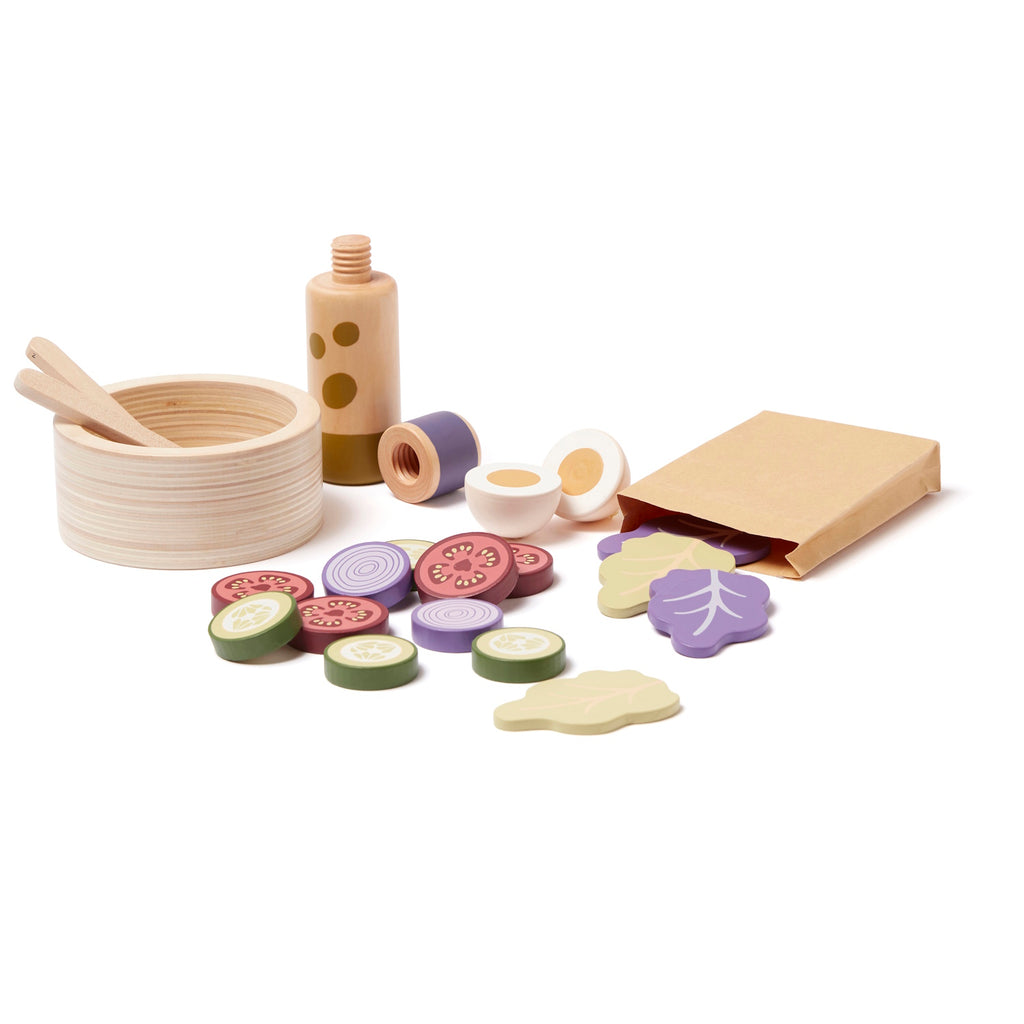 Wooden toy salad set with a bowl, utensils, slices of vegetables, and a bottle. Items are colorful, playful, and spread out, conveying a fun, culinary theme.