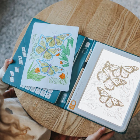 An illuminated drawing pad showing a butterfly sketch next to a finished, colored butterfly drawing.