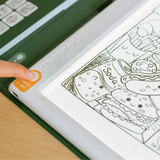A finger presses the power button on an illuminated Kidywolf drawing pad featuring cartoon food illustrations.