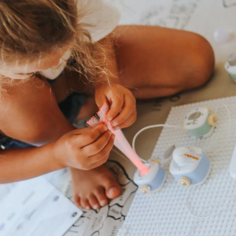 A young child plays with an electrical building blocks toy kit featuring a glowing fiber optic component.