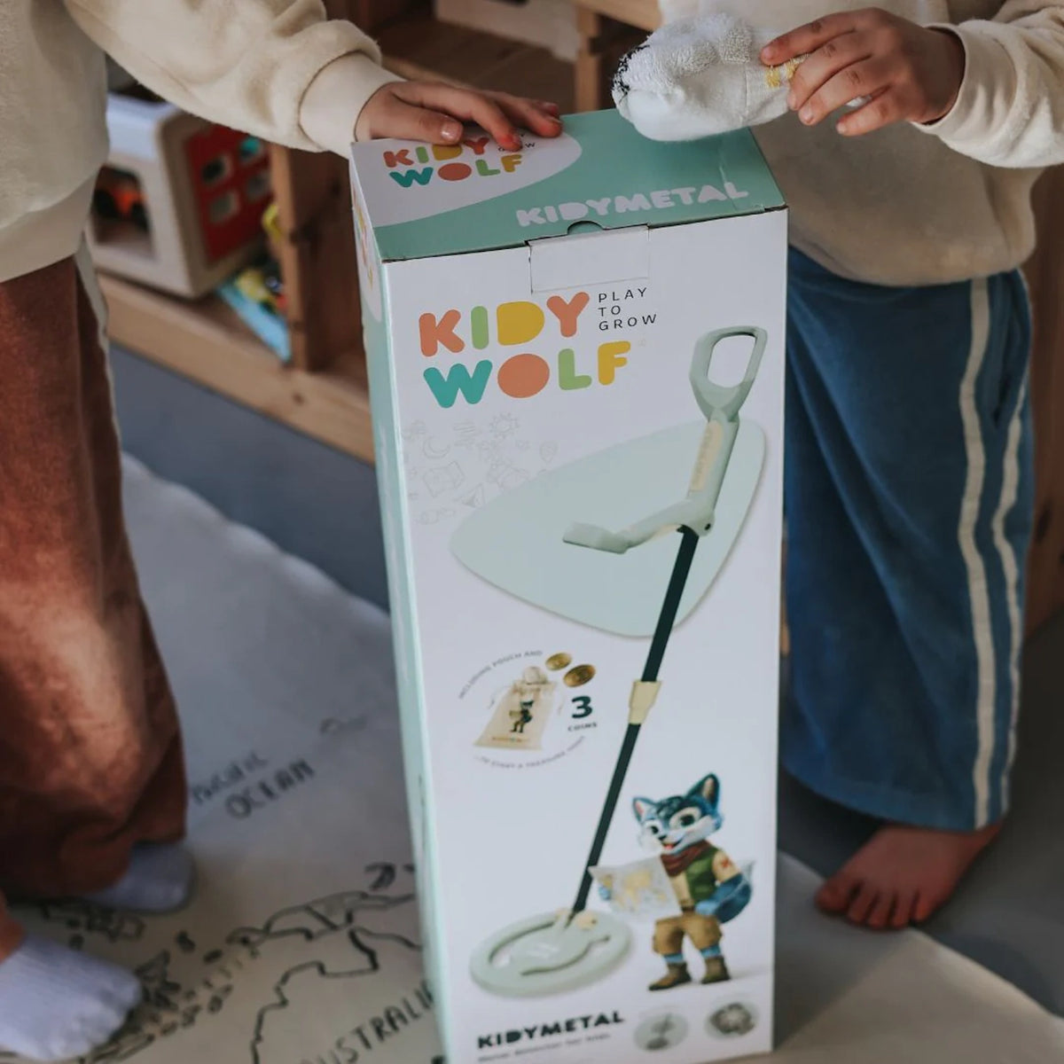 Two children touching a Kidywolf Kidymetal toy box with a metal detector graphic.