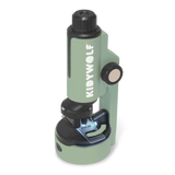 A compact green microscope labeled "KIDYWOLF" on a white background. It features a black rotating focus knob and an illuminated stage area.