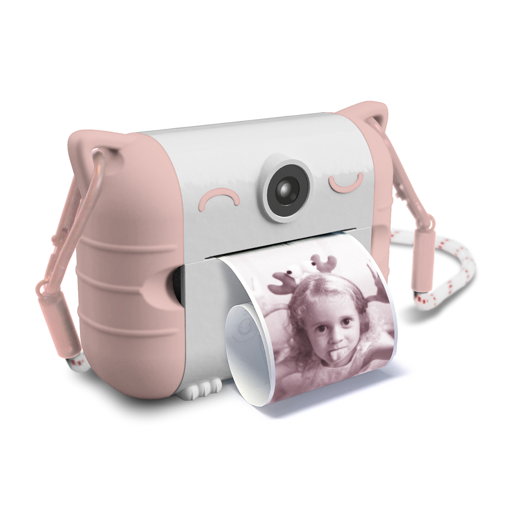 Cute pink and white toy camera with cat ears, printing a black and white photo of a child smiling. The design is playful and whimsical.