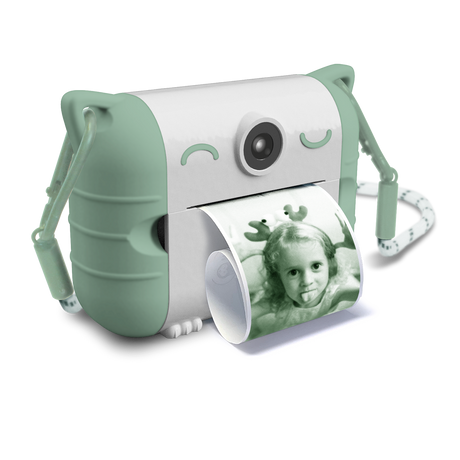 Cute white and mint green instant camera with cat ears prints a photo of a child making a playful face. The design is whimsical and fun.