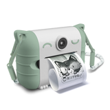 Cute white and mint green instant camera with cat ears prints a photo of a child making a playful face. The design is whimsical and fun.