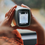 Child's hands hold a small digital camera with a screen displaying a blurred outdoor scene. The focus is on exploration and curiosity.