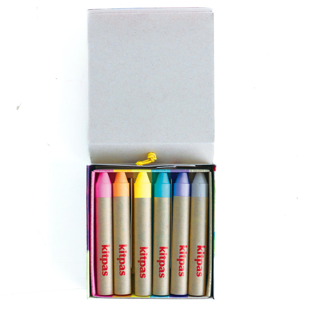 Open box of Kitpas crayons with six vibrant colors: pink, orange, yellow, turquoise, blue, and purple. Each crayon has a cardboard sleeve.