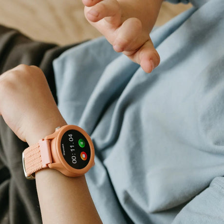 A child wearing a coral-colored smartwatch with a stopwatch timer running on the screen.