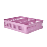 Pink plastic storage basket with slotted sides and two internal dividers, set against a white background. The basket design suggests functionality and simplicity.
