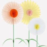 Close-up of three stand-up paper flowers with accordion fan petals in pastel peach, yellow, and white.