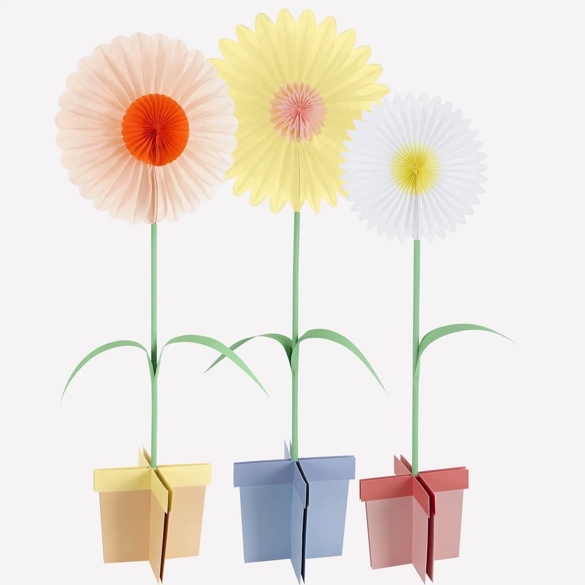 Three stand-up paper flower decorations in peach, yellow, and white, set in colorful pot stands.