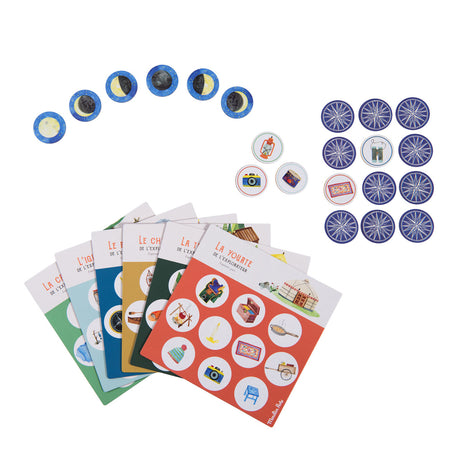 A selection of colorful game cards and circular tokens featuring various illustrated objects, such as the moon phases, cameras, and bicycles, laid out on a white background.