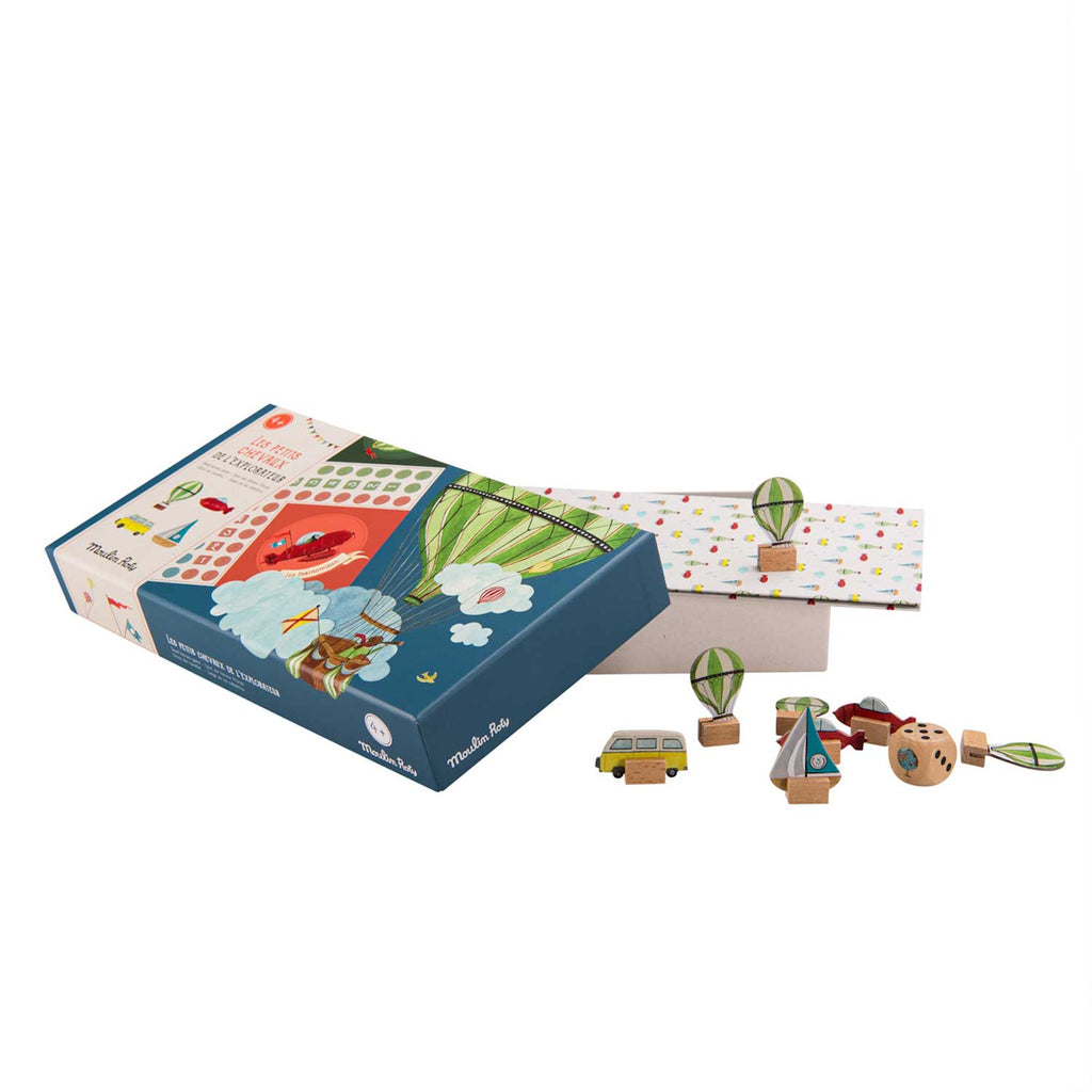 Box of a children's board game, featuring a colorful hot air balloon design on the cover. Assorted wooden game pieces are spread nearby.