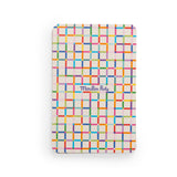 A rectangular card with a colorful grid pattern and the cursive text "Moulin Roty" in a central blue box.