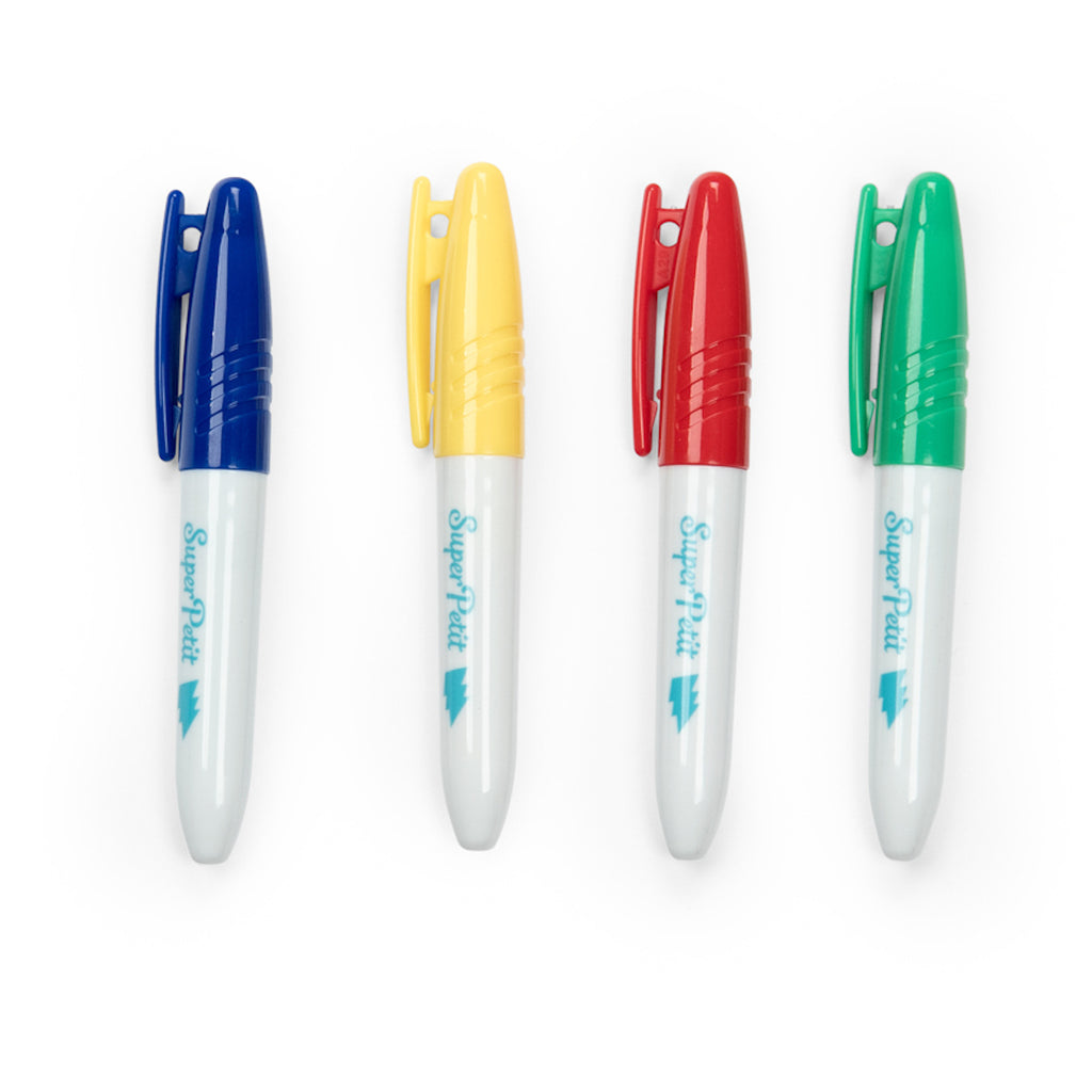 Four white markers with blue, yellow, red, and green caps are aligned horizontally. Each has a clip, creating a vibrant and organized appearance.