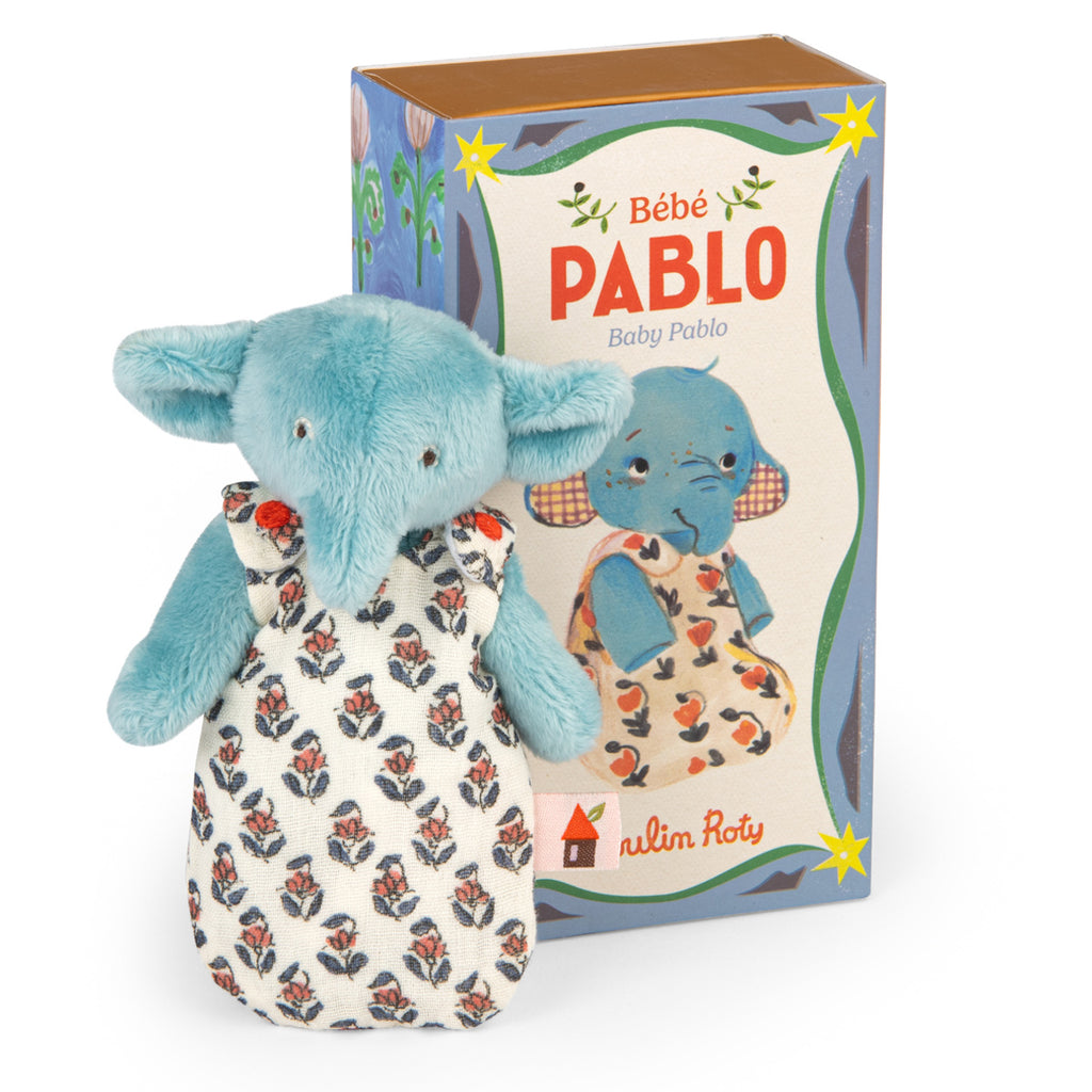 Cute blue stuffed elephant in a floral outfit stands in front of a matching box labeled "Bébé Pablo." The soft toy exudes a playful and whimsical charm.