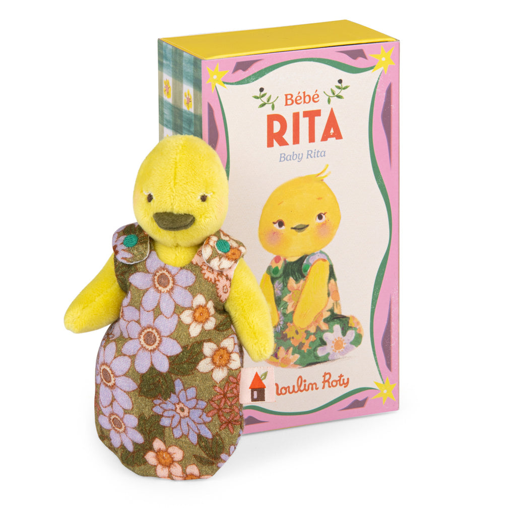 Yellow plush duck toy wearing a floral dress stands in front of a box featuring a matching illustration and the text "Bébé Rita". Bright, cheerful tone.