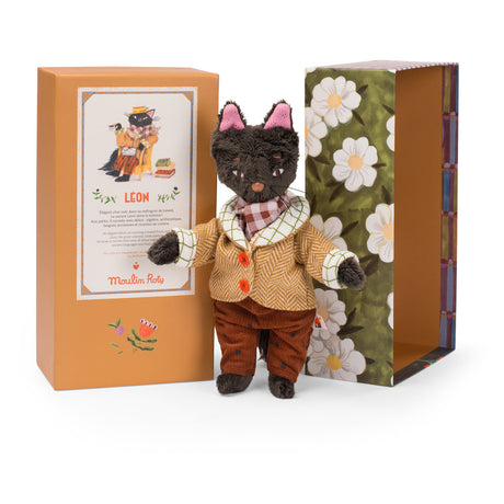 Moulin Roty Leon the cat plush toy in a tweed coat standing between its orange and floral illustrated boxes.