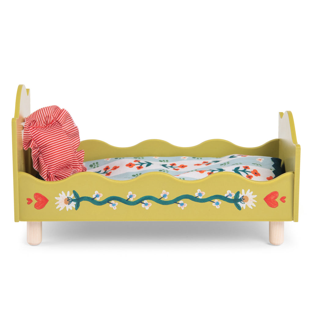 A small, decorative wooden doll bed painted yellow with floral designs. It features a red-striped pillow and a colorful floral-patterned mattress.