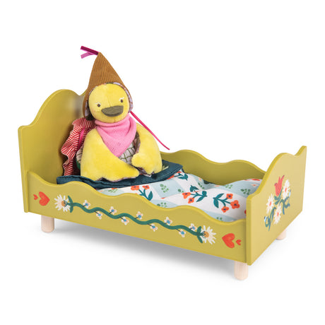 Yellow plush bird doll sitting in a painted wooden toy bed with floral bedding.