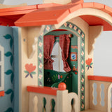 Decorative wooden toy caravan house featuring colorful folk art, floral designs, and red gingham curtains.